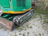 a green and yellow excavator that is sitting on the ground