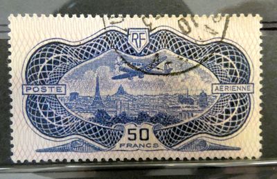 the stamp is blue and white with a picture of a plane flying over a city
