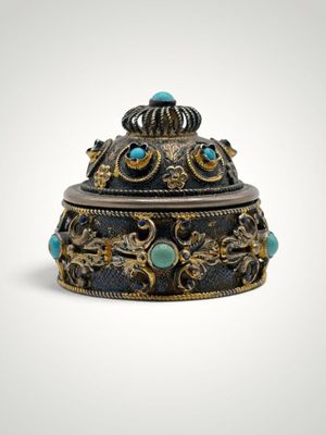 an ornately decorated box with turquoise stones on a white background