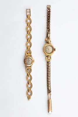 two watches are sitting side by side on a white surface