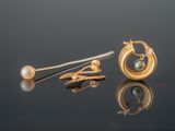 two gold earrings with pearls and a pearl on a reflective surface