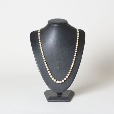 un collier de perles blanches sur un mannequin noir