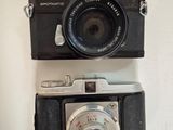 two cameras sitting on a white surface one has a black camera and the other has a silver camera
