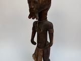 une statue en bois représentant une femme avec un oiseau sur la tête