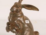 bronze sculpture of a rabbit sitting on its hind legs with a tag on it ' s ear