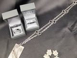 un gros plan sur un collier en argent et une paire de boucles d'oreilles posés sur un tissu noir