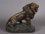 bronze statue of a lion on a rock on a gray background