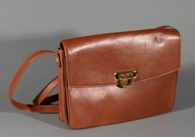 brown leather handbag with gold buckles on a grey background