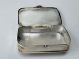 a small silver box with a handle on a white surface