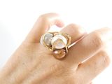 a woman ' s hand holding a pearl and gold ring