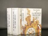 trois livres posés sur une table, à côté d'une horloge