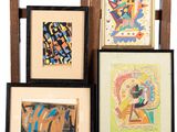 Plusieurs œuvres d'art encadrées sont exposées sur une étagère devant un fond blanc.