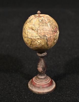 un vieux globe posé sur un socle en bois, sur une surface noire