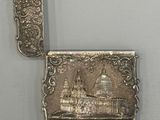 an antique silver cigarette case with a picture of a castle on it