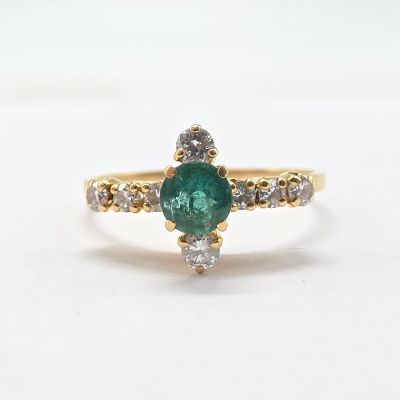 a close up of a green emerald and diamond ring on a white surface