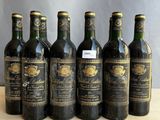 six bottles of wine are lined up in a row on a table