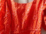 an orange dress hanging on a hanger on a white wall