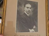 a picture of a man in a suit and tie holding a framed picture