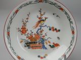 an orange and white plate with a bird and flowers design on it