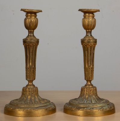 une paire de bougeoirs anciens en laiton posés sur une table en bois