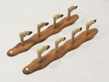 three wooden ducks are standing on a long wooden stand