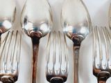 five spoons and a fork on a white surface