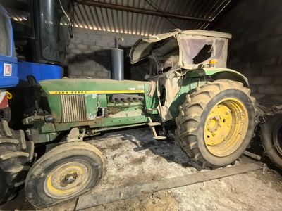 a green tractor that is parked in a barn