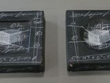 two black boxes with drawings on them are sitting on a table