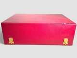a red box with gold handles sitting on a white surface