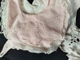 a pink bib with white lace on it on a black surface