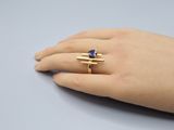 a woman ' s hand holding a ring with a blue stone on it