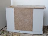 a white box with a brown top sitting on the ground next to a white wall