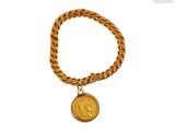 a close up of a gold chain bracelet with a coin on it