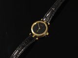 une montre-bracelet plaquée or, avec un cadran noir et un bracelet en cuir noir