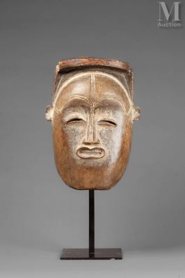 a wooden mask on a stand with a gray background