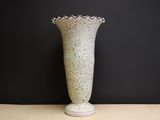 a white vase sitting on a table with a black wall in the background