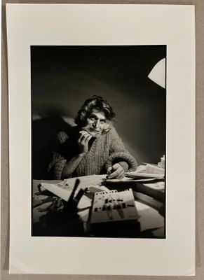 photographie en noir et blanc d'une femme assise à un bureau avec une calculatrice