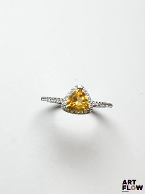 un gros plan d'une bague sertie d'un diamant jaune sur une surface blanche