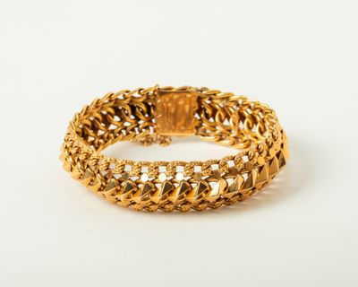 gros plan d'un bracelet en or sur une surface blanche