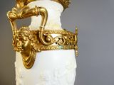 un vase blanc muni d'une anse dorée, posé sur une table