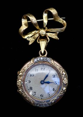 une petite horloge en or ornée d'un nœud