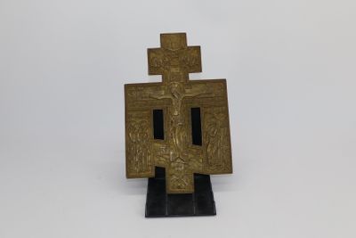 an old bronze cross on a black stand on a white background