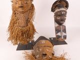 Plusieurs masques africains sont exposés sur un fond blanc.