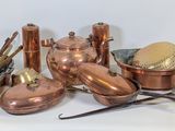 un grand nombre de casseroles et de poêles en cuivre posées sur une table