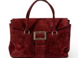 un sac à main en daim rouge orné d'une boucle métallique sur le devant