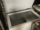 an open freezer in a kitchen with a lot of stuff on the counter