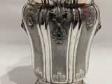 a silver vase that is sitting on a white surface