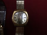 une montre-bracelet en or posée sur une table à côté d'un miroir