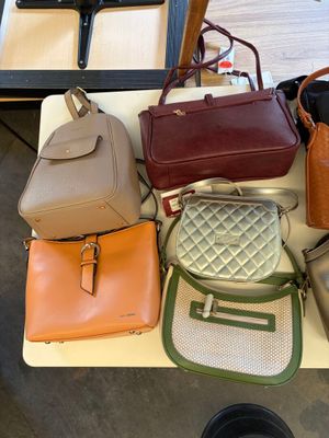 many bags and purses on a table in a room