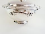 a silver bowl with a lid on a white table